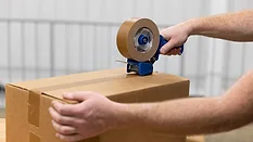 Sealing a Corrugated Shipping Box Worker sealing a corrugated shipping box with a hand tape dispenser.