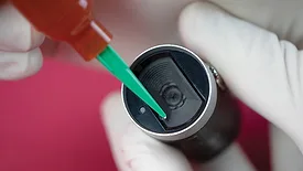 Adhesive being dispensed onto a medical device component with a precision applicator.