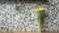 Alt text: Black, white and gray peel and stick tile in a kitchen with yellow flowers in a vase 