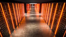 Servers with orange lights illuminating the corridor in a data center