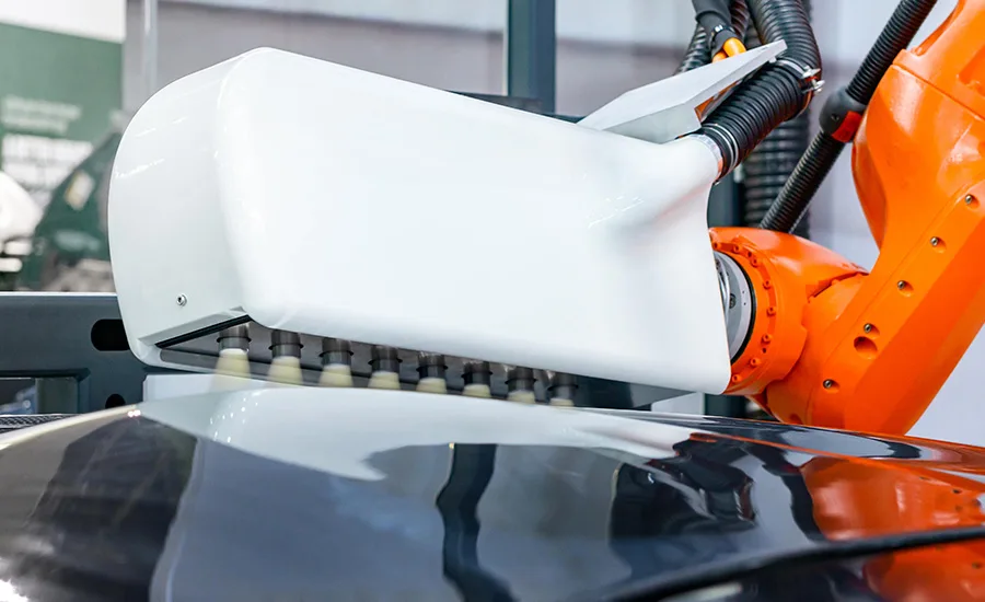 Industrial robot performing plasma surface treatment on an automotive component