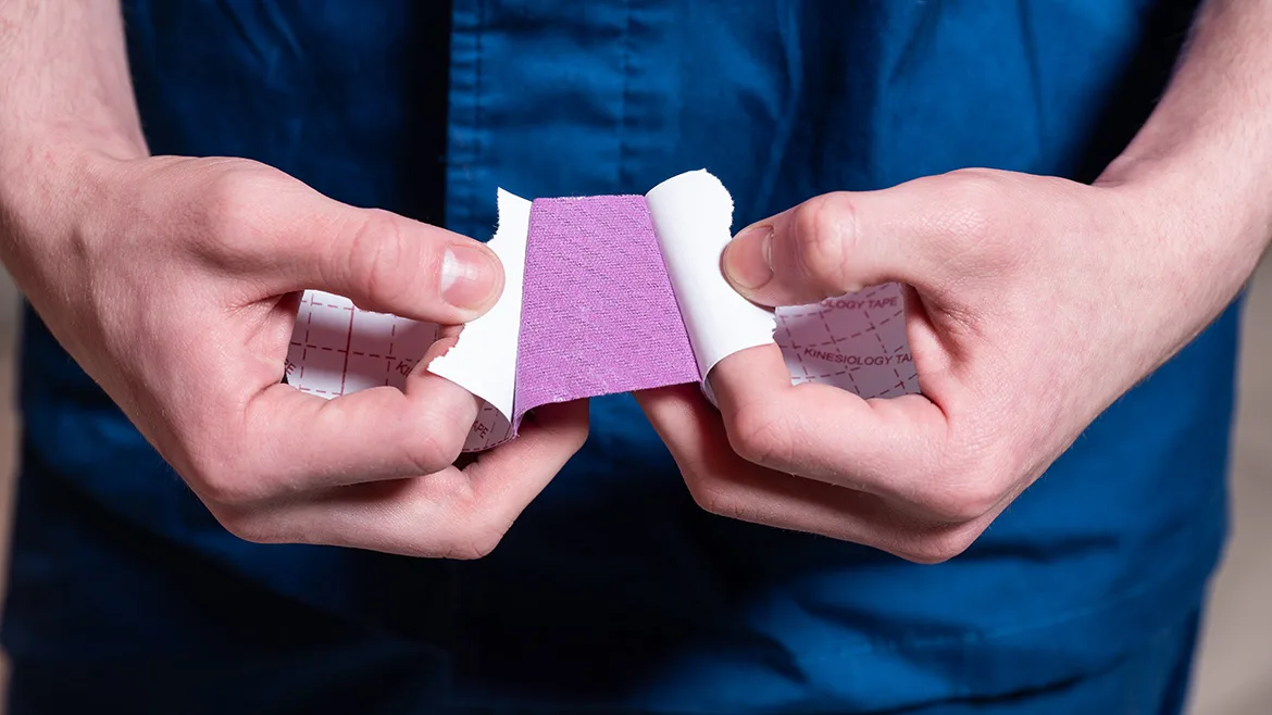 A rehabilitation doctor prepares kinesiology tape for a patient