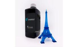 Photo of bottle of additive manufacturing resins next to small replica of the Eiffel Tower