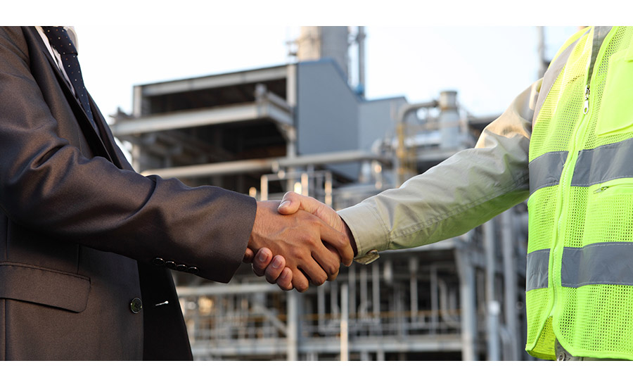 Image of two people shaking hands in front of an industrial facility