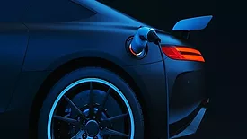 Image of the back of a blue electric vehicle with the charger attached. 