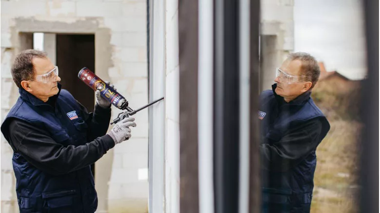 Photo of worker applying sealing foam around windows