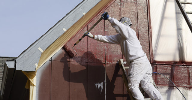 painting building exterior with areas protected by protective adhesives