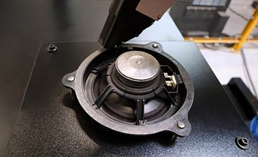The application head maneuvers the tape head around the circumference of this automotive speaker. RoboTape can apply tape faster than humans -- up to 10 inches per second.
