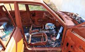 Rusted car in junkyard stripped down to the frame