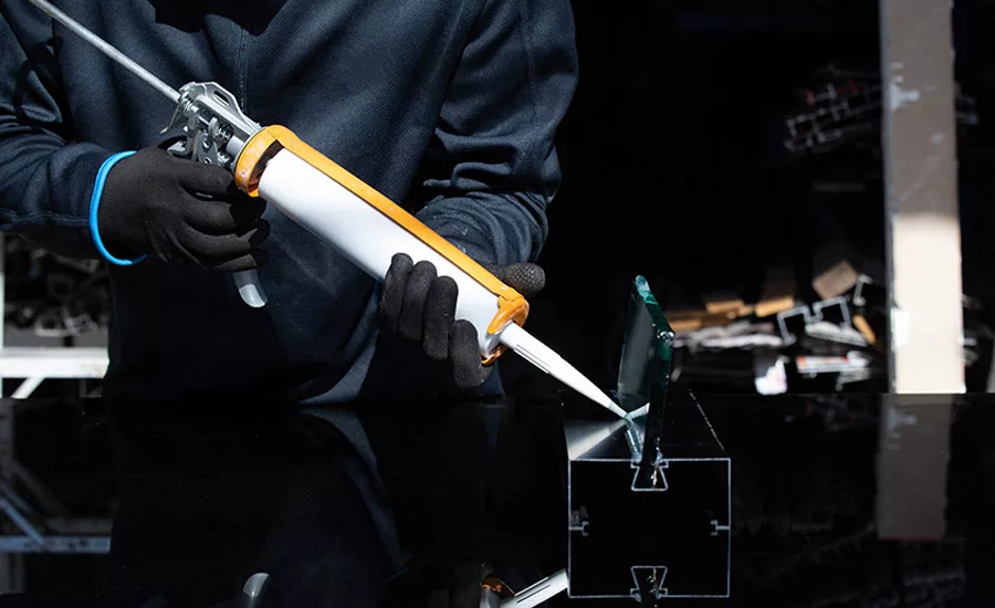 man using caulk gun to add adhesive to object