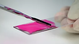 Photo of red Master-Bond UV15RCL on a clear plate