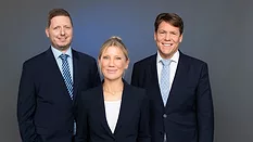 Picture of two men and one woman in dark suits