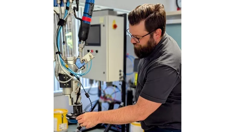 Picture of a man in front of an adhesive dispensing machine