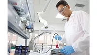 Picture of man in white coat in laboratory holding container with pink liquid