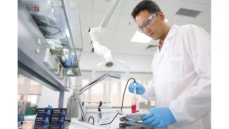 Picture of man in white coat in laboratory holding container with pink liquid