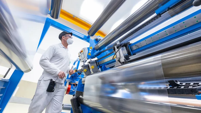Picture of man standing at machine extruding specialty films