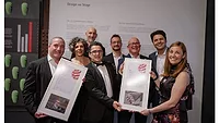 Picture of people holding up two awards