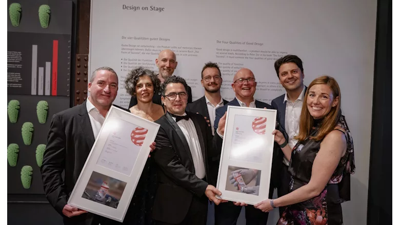 Picture of people holding up two awards