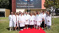 Picture of people standing on a red carpet in front of a new building