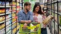 Two people looking at a box of food at a grocery store. 