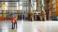 Two people in safety vests standing near the doors of a modern warehouse.