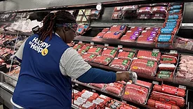 Picture of woman in a Walmart vest at a meat isle