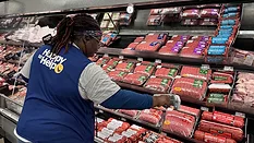 Picture of woman in a Walmart vest at a meat isle