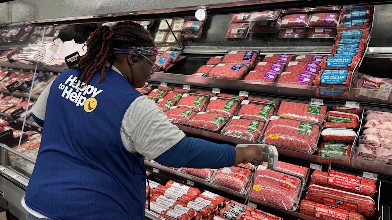 Picture of woman in a Walmart vest at a meat isle