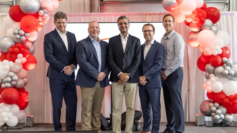 Picture of four men standing under an arch or red and pink balloons