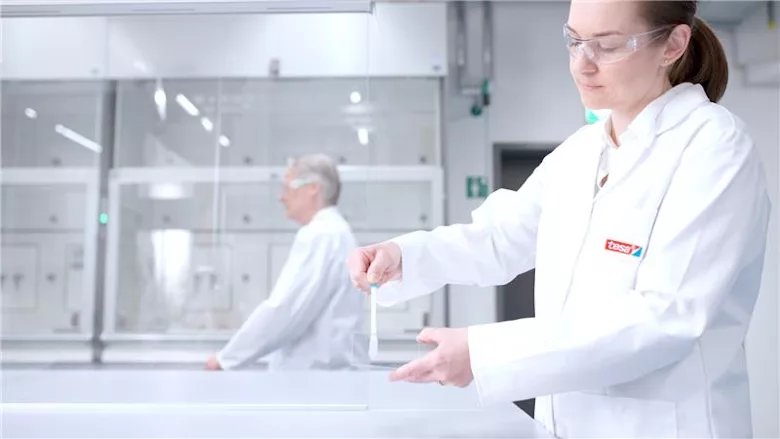 Picture of a woman in a white lab coat testing an adhesive bond