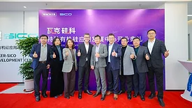 Picture of seven men and two women standing in front of a sign and giving a thumbs up.