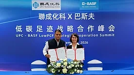A woman and a man standing in front of a blue backdrop holding signed documents