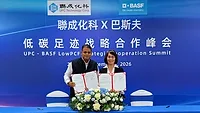 BASF and UPC strategic partnership A woman and a man standing in front of a blue backdrop holding signed documents