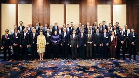Picture of a group of people standing togther in front of a decorative wall