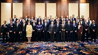 Picture of a group of people standing togther in front of a decorative wall