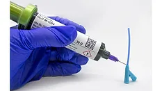 Picture of hands in a blue glove dispensing an adhesive from a syringe