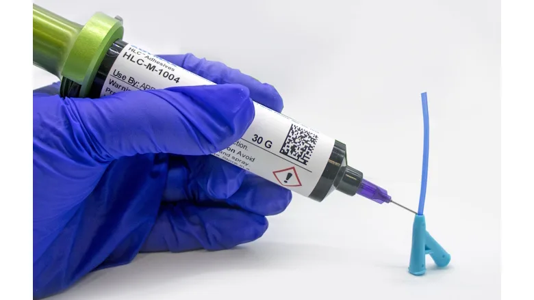 Picture of hands in a blue glove dispensing an adhesive from a syringe