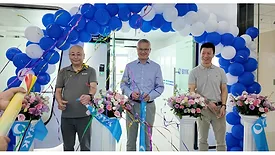 Picture of three men standing under an arch of blue and white balloons