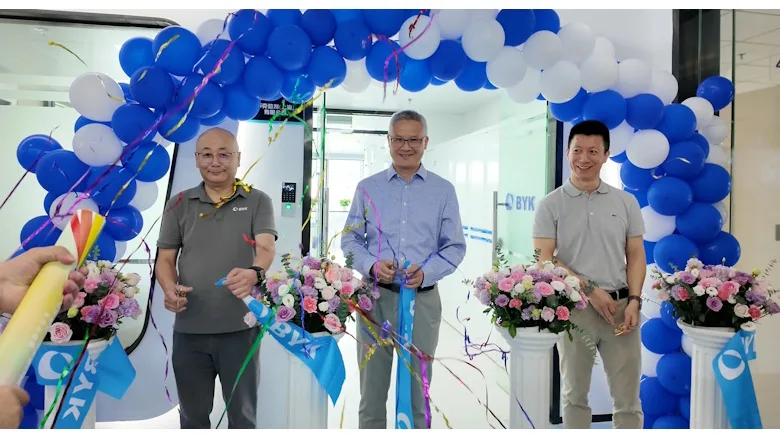 Picture of three men standing under an arch of blue and white balloons