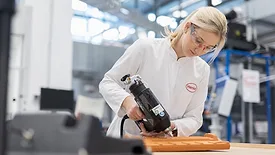 Women  in a labcoat dispensing a hot melt adhesive on a roof tile