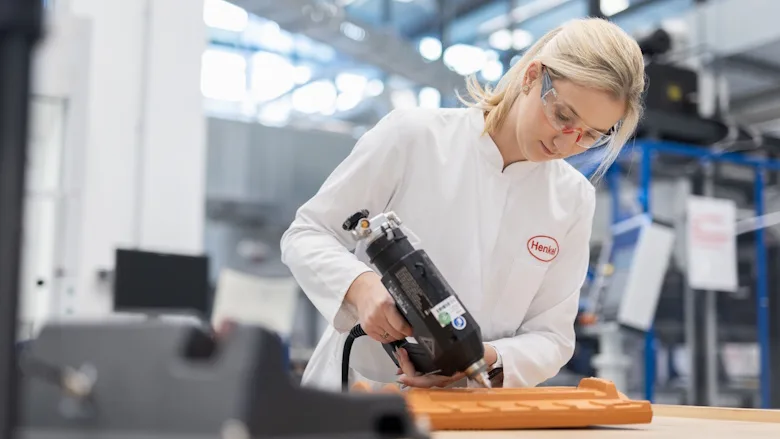Women  in a labcoat dispensing a hot melt adhesive on a roof tile