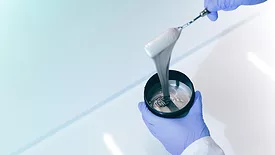 Picture of a gloved hands holding a container of ink
