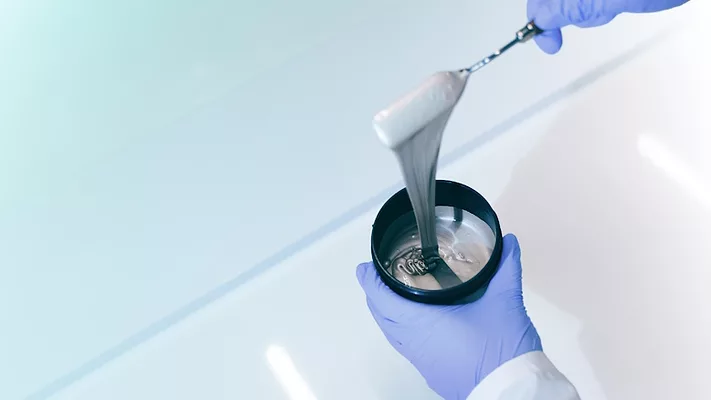 Picture of a gloved hands holding a container of ink
