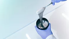 Picture of a gloved hands holding a container of ink