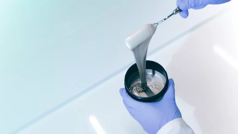 Picture of a gloved hands holding a container of ink