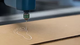 Picture of an adhesive being dispensed on cardboard