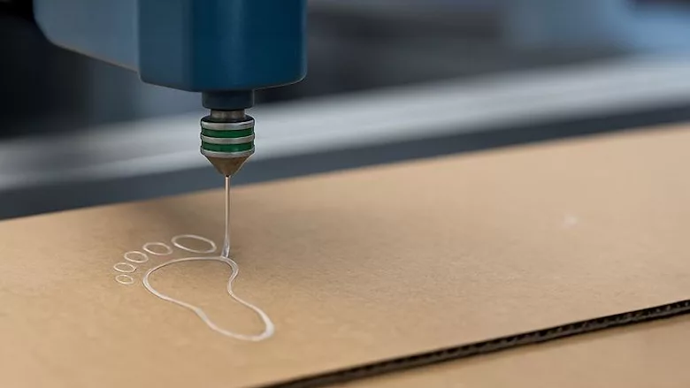 Picture of an adhesive being dispensed on cardboard