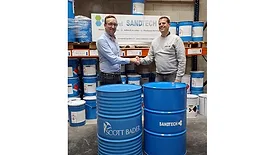 Picture of two men shaking hands in front of large blue drum containers