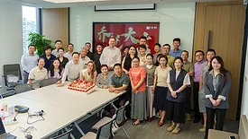 Picture of a group of people around a table with a cake on it