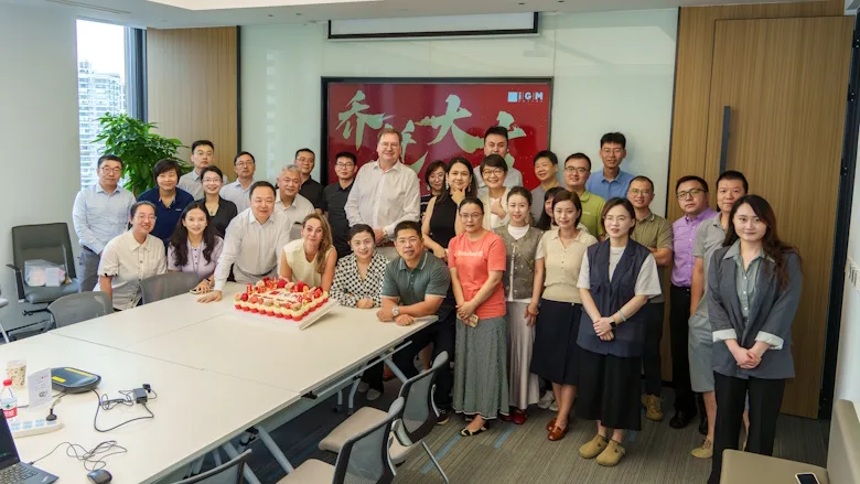 Picture of a group of people around a table with a cake on it